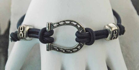 Black cord bracelet with silver horseshoe charm, horse-themed jewelry.