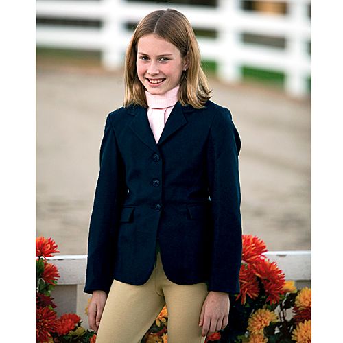 Young girl smiling wearing Tuffrider equestrian show jacket outdoors.